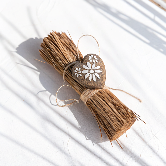 Fago coco cœur bohème en coque de coco naturelle avec motifs floraux peints main blancs, lié à un faisceau de vétiver pour une déco artisanale apaisante